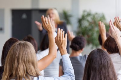 People raising hands in meeting conference