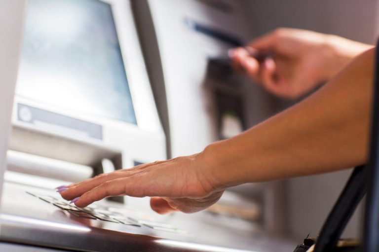 Close up of unrecognizable female person withdrawing money from ATM.